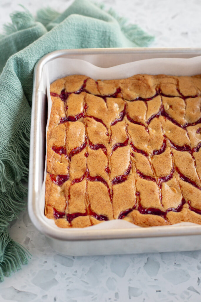 White chocolate raspberry jam blondies freshly baked, cooling in a metal tin.