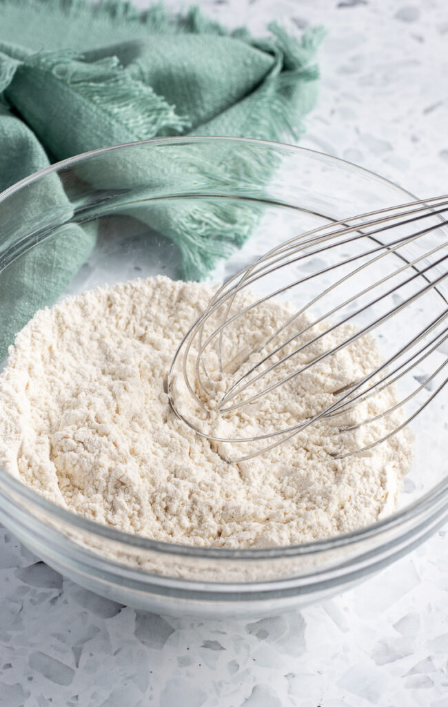 Metal whisk resting in a bowl of dry ingredients, ready for mixing.