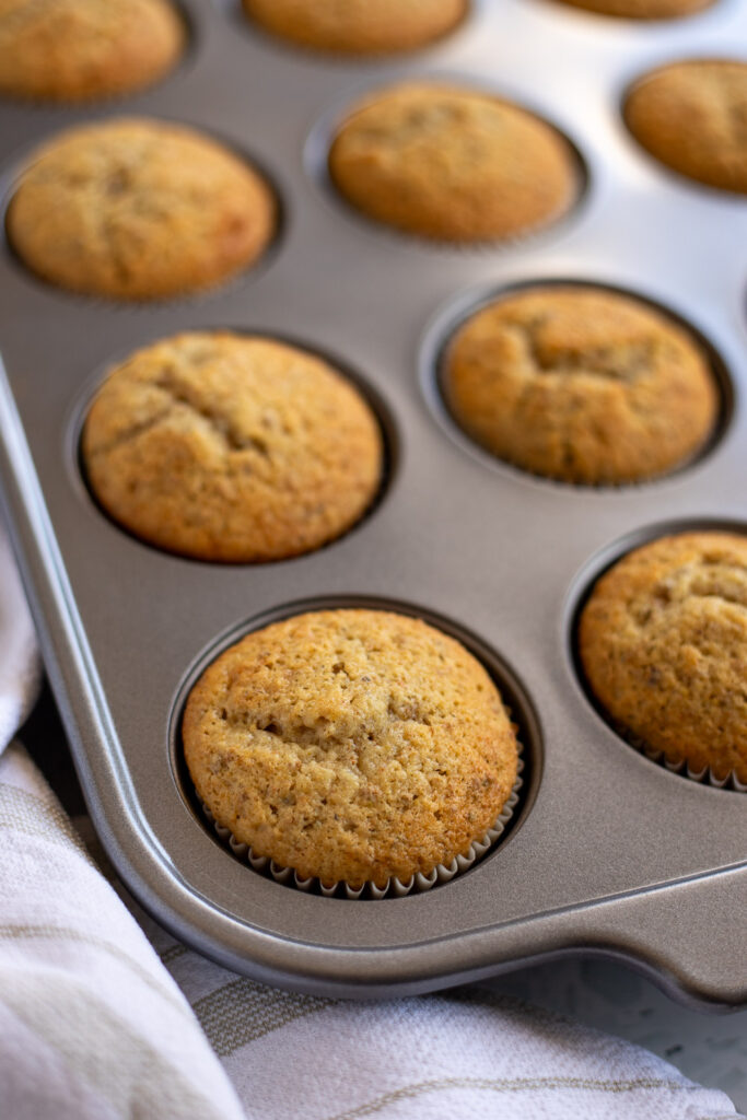 Freshly baked cupcakes cooling in an aluminium muffin tin. 