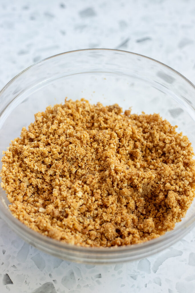 Biscuit base and crumble topping mixture ready in a small glass mixing bowl.