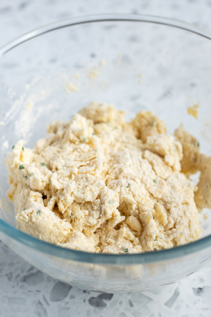 Crumbly biscuit dough in a mixing bowl, ready to be turned out onto a floured surface for shaping and layering.