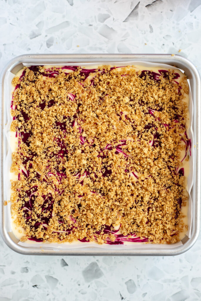 Top-down view of blackberry pear crumble cheesecake bars assembled and ready for baking.