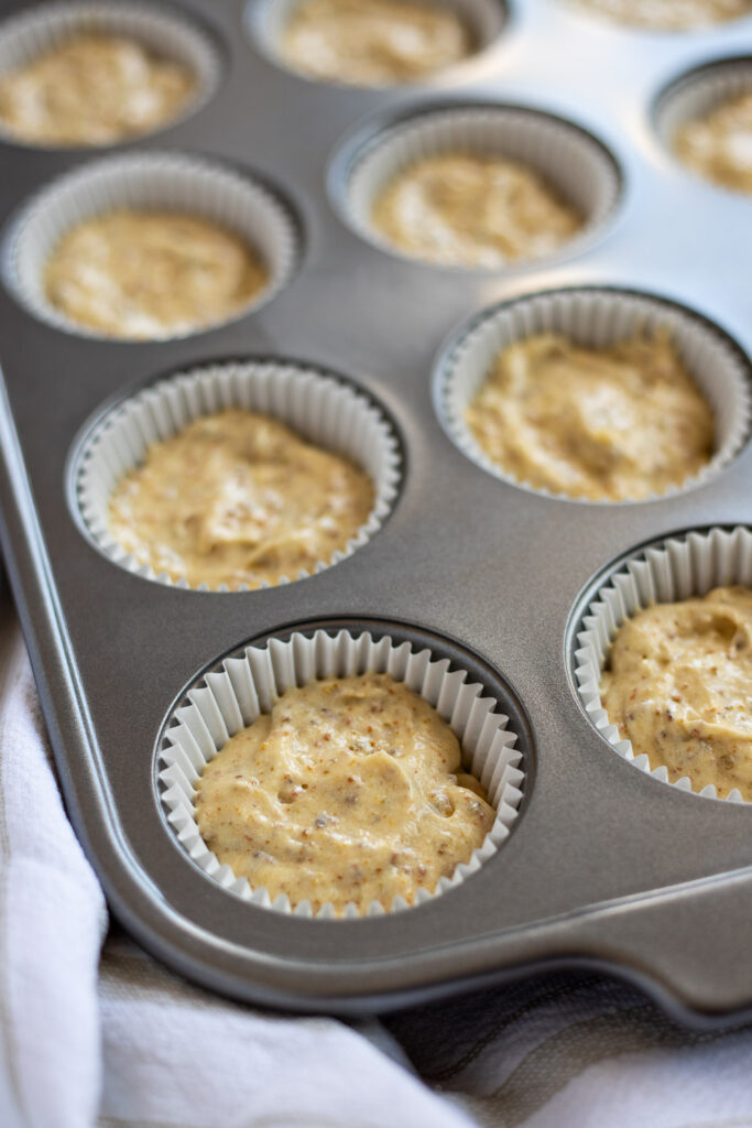Pistachio cupcake batter evenly scooped into cupcake liners.