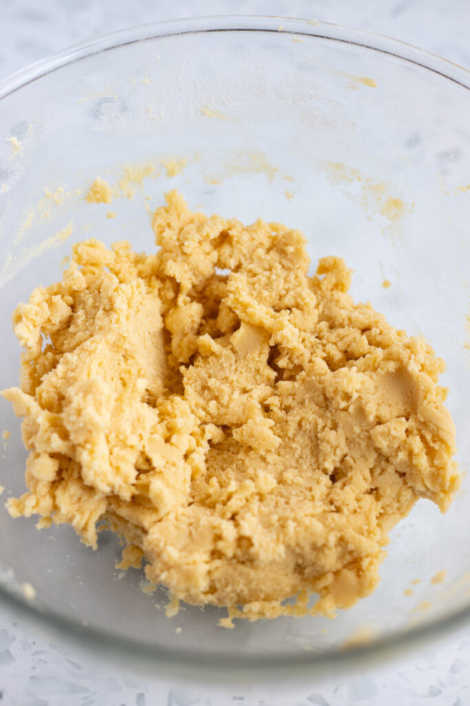 Crumbly shortbread dough in a mixing bowl, before being brought together.