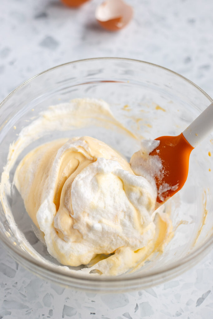 Egg whites being gently folded into a mascarpone mixture to create a light and airy tiramisu filling.