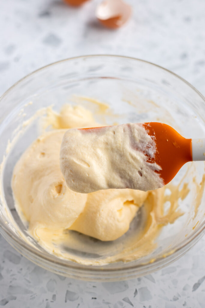 Tiramisu filling on a rubber spatula, showing smooth, creamy consistency, ready for assembling the dessert.