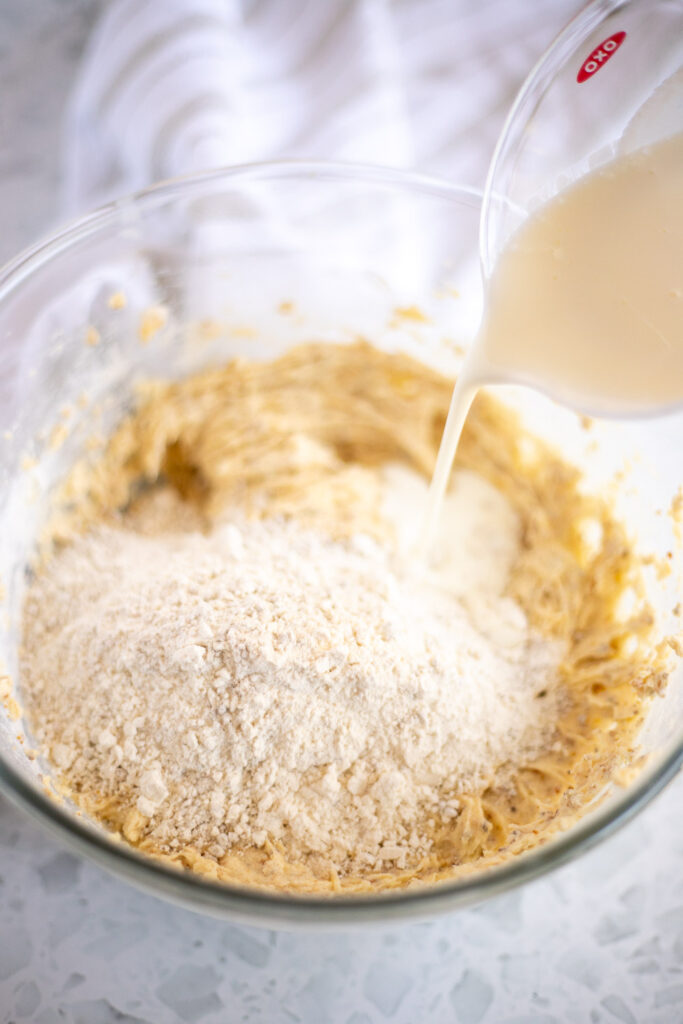 Action shot of buttermilk added to pistachio cupcake mixture, dry ingredients not yet mixed in.