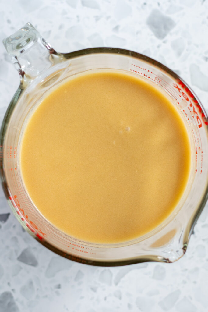 Top-down view of glass measuring jug with whisked wet ingredients.