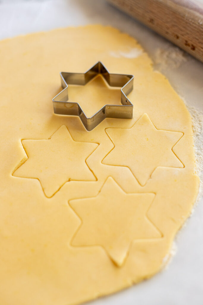 Close-up of star cookie cutters cutting shapes from lemon shortbread dough.