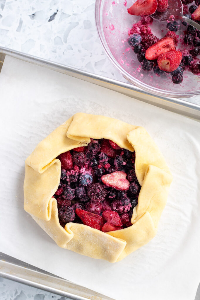 Edges of galette dough folded over the berry and frangipane filling, forming a rustic open-faced tart.