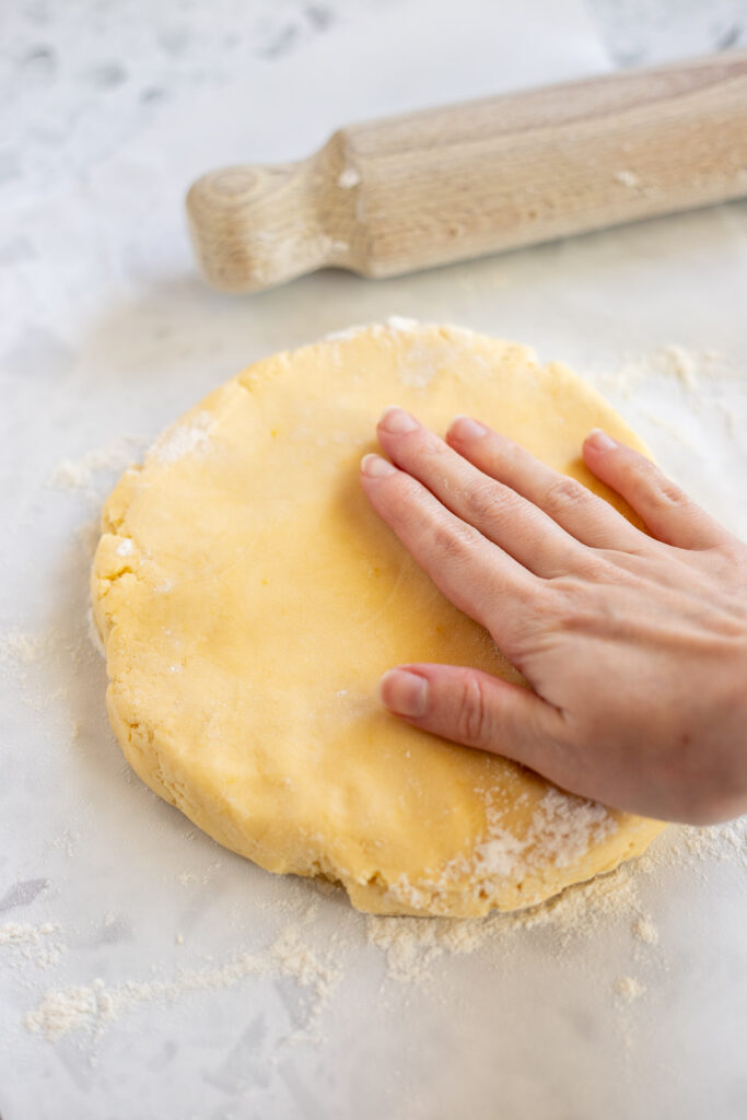 Hand shaping lemon shortbread dough into a disc.