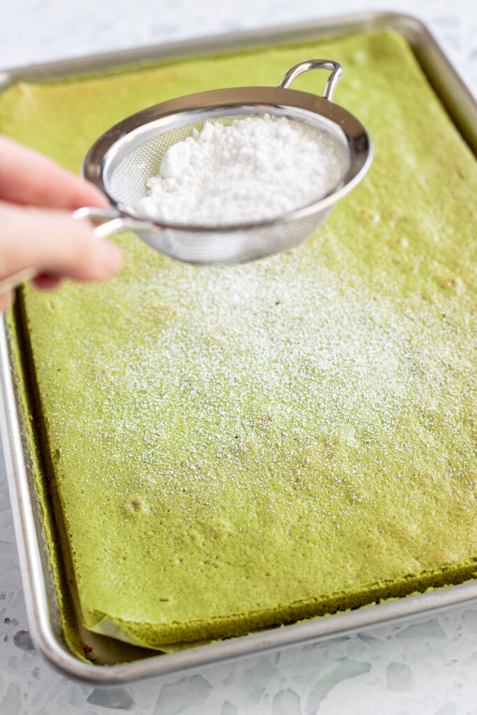 Sifting icing sugar over freshly baked and steamed matcha sponge.