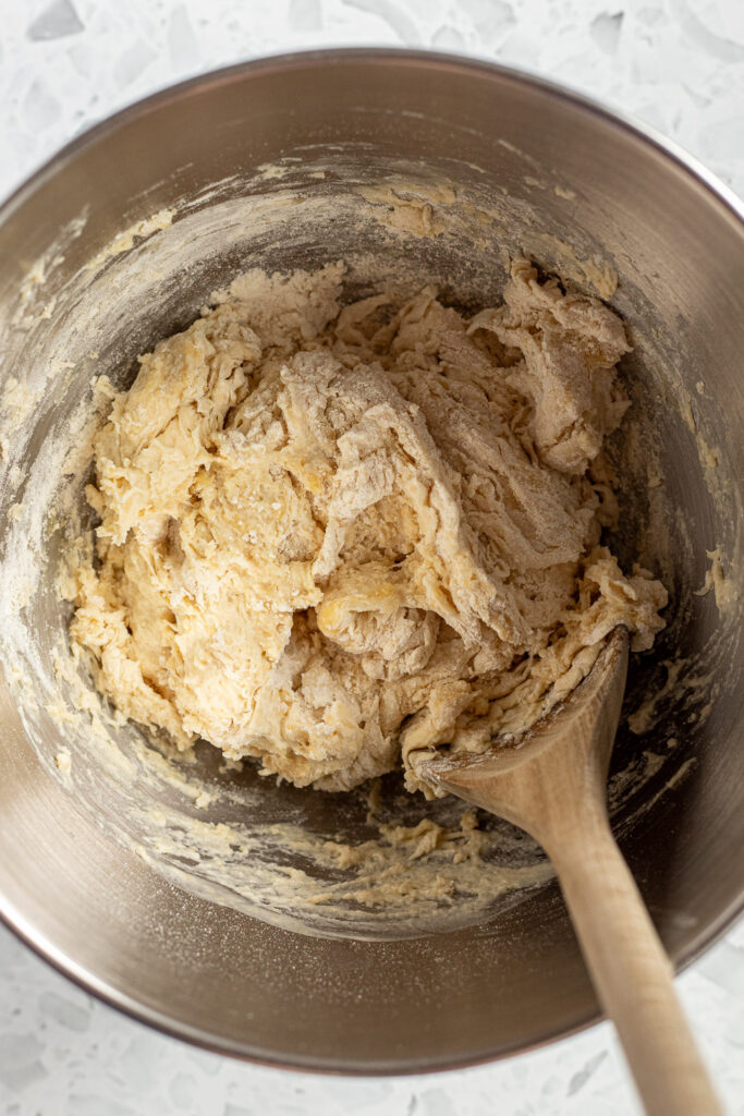 Shaggy pizza dough in a stand mixer bowl, ready to be kneaded for garlic knots.