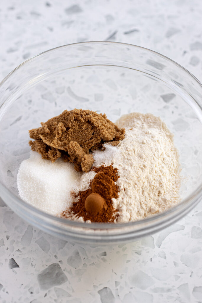 Dry ingredients being added to a bowl to make cinnamon streusel topping