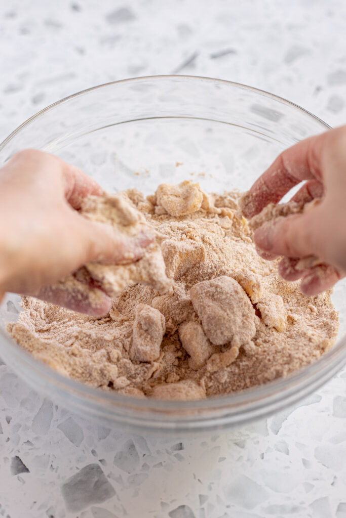 Hands rubbing butter into dry ingredients