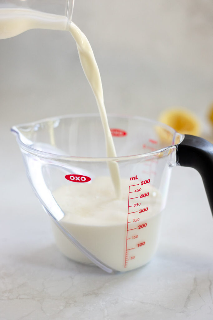 Milk being poured into a measuring jug with lemon juice to make a buttermilk substitute