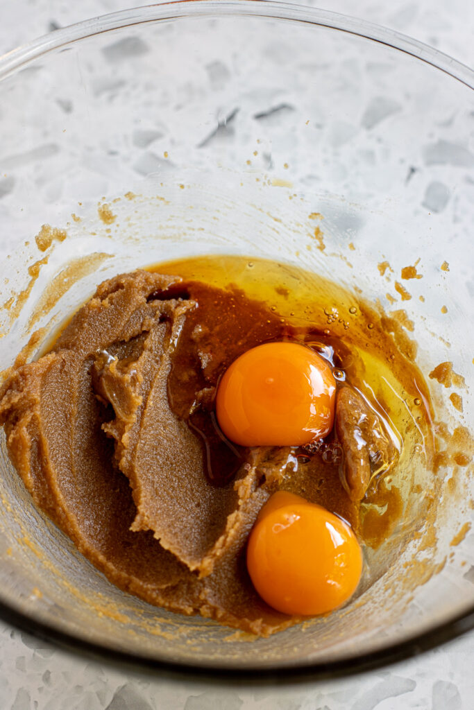 eggs and vanilla added to mixing bowl of grainy butter and sugar mixture