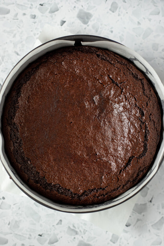 Top-down view of baked chocolate Guinness cake in a tin with a cracked top and slightly sunken middle