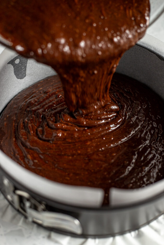 Chocolate Guinness cake batter being poured into a lined springform tin