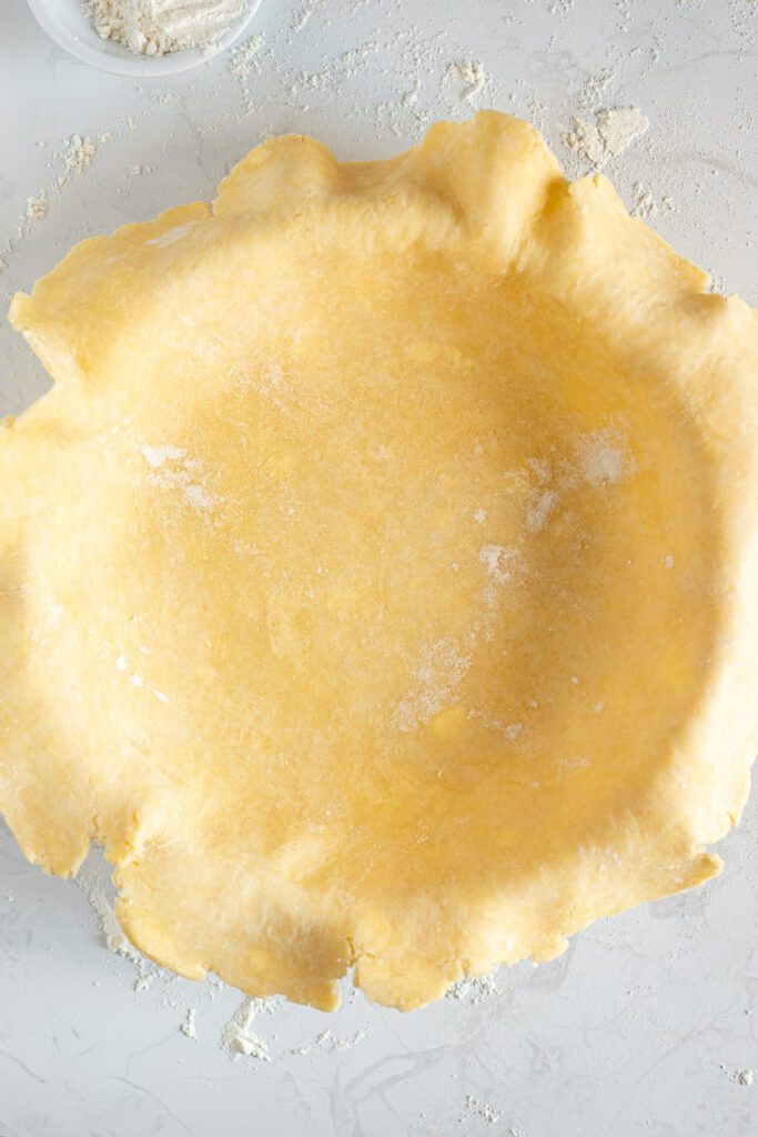 Pie crust draped over pie dish.