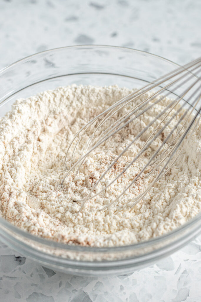 Bowl of combined dry ingredients for snickerdoodles with a whisk resting inside