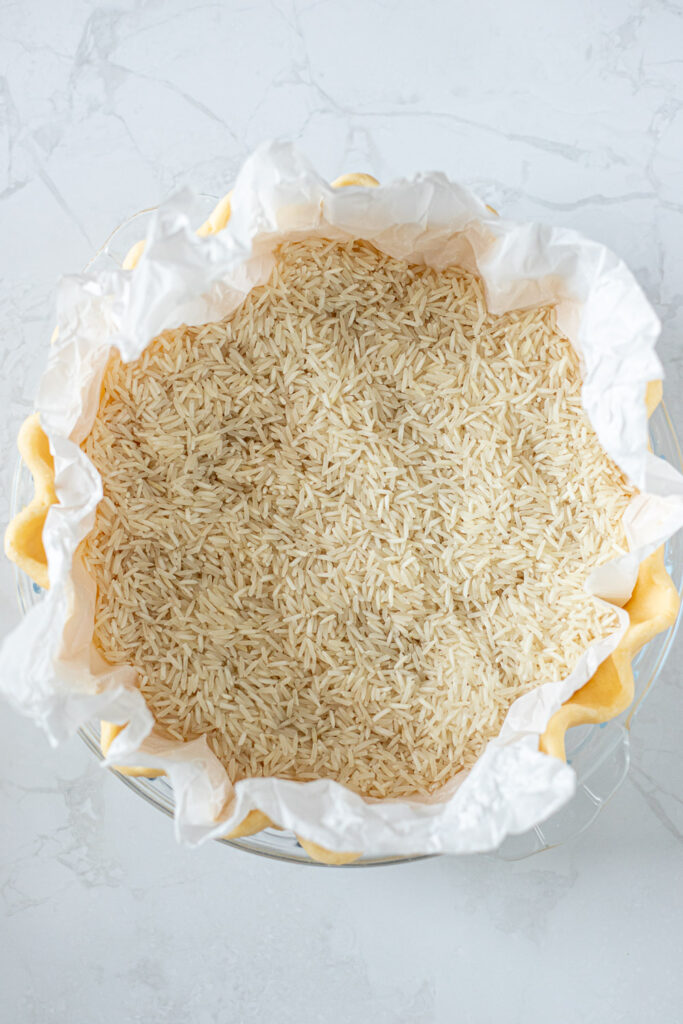Un-baked pie crust lined with crumpled baking paper and filled with dried rice.