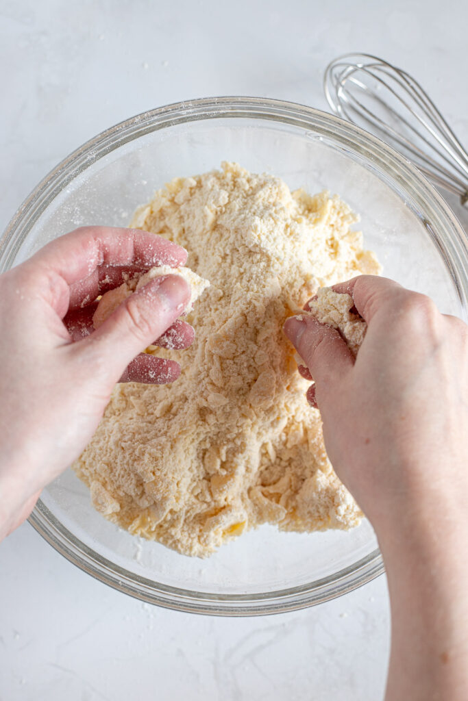 Working butter into flour by rubbing butter pieces between fingertips and thumbs.