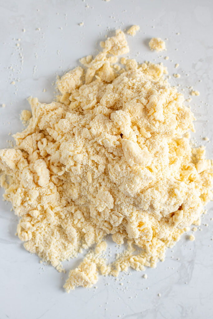 Shaggy, crumbly pie dough turned out onto a floured surface.