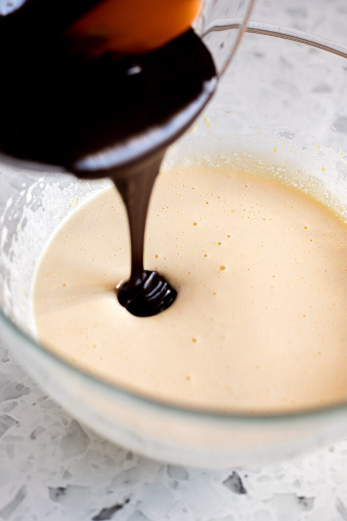 Pouring the chocolate mixture into the beaten eggs and sugar.