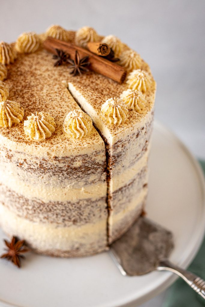 Close-up of a slice of vanilla chai cake being lifted away from the cake on a metal cake server.